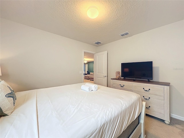 bedroom featuring light colored carpet and a textured ceiling