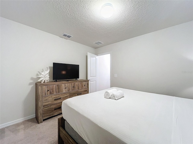 bedroom with a textured ceiling and light carpet