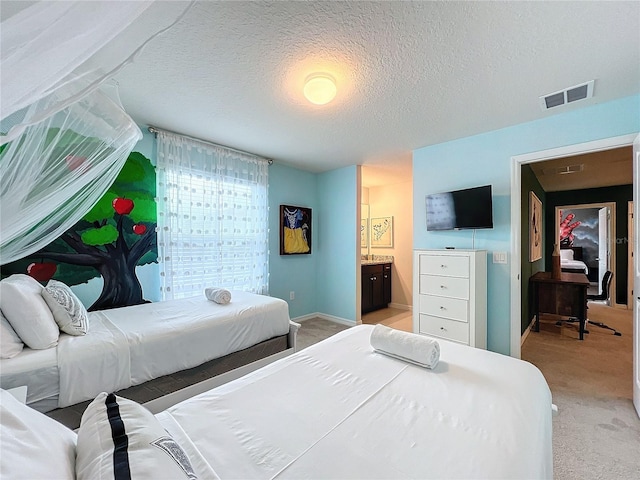 bedroom featuring a textured ceiling, light colored carpet, and ensuite bathroom