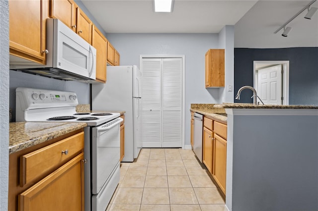 kitchen with sink, light stone counters, track lighting, white appliances, and light tile patterned floors