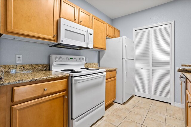 kitchen with light stone countertops, white appliances, and light tile patterned floors