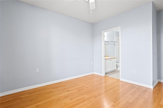 unfurnished bedroom featuring ensuite bathroom, a walk in closet, light hardwood / wood-style flooring, ceiling fan, and a closet