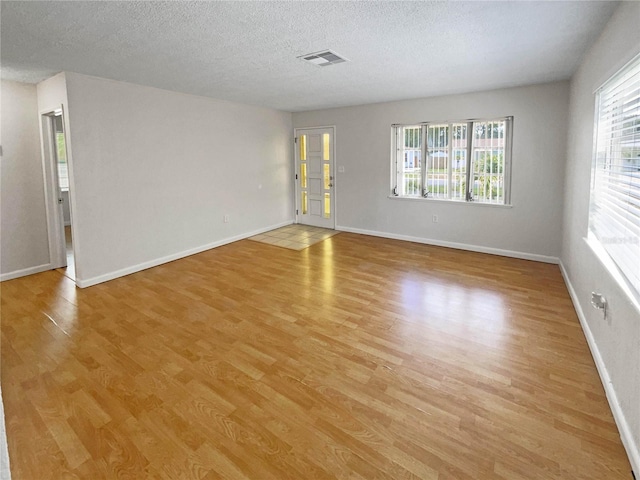 unfurnished room featuring light hardwood / wood-style floors and a textured ceiling