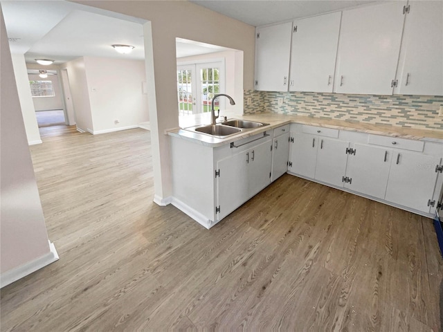 kitchen with white cabinetry, sink, french doors, backsplash, and light hardwood / wood-style floors