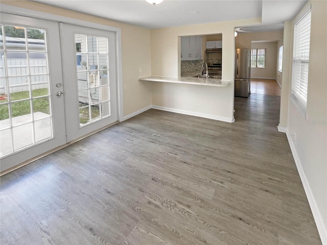 unfurnished living room with a wealth of natural light, french doors, and dark wood-type flooring