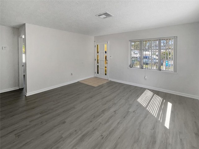 unfurnished living room with visible vents, a textured ceiling, baseboards, and dark wood-type flooring