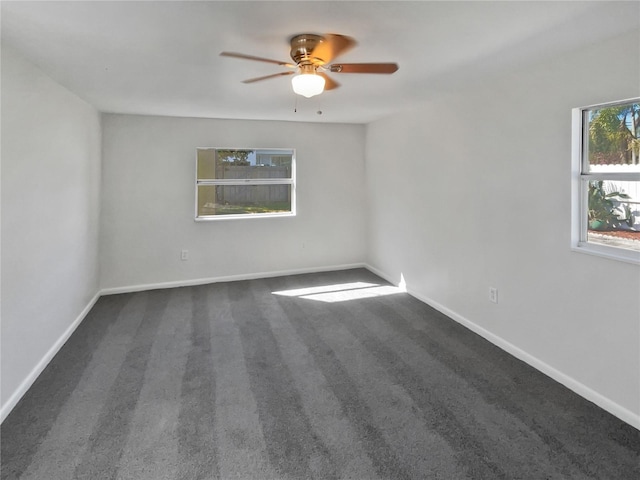 carpeted spare room with a ceiling fan and baseboards