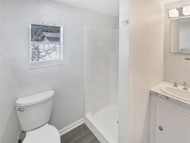 full bathroom with toilet, vanity, wood finished floors, baseboards, and a walk in shower