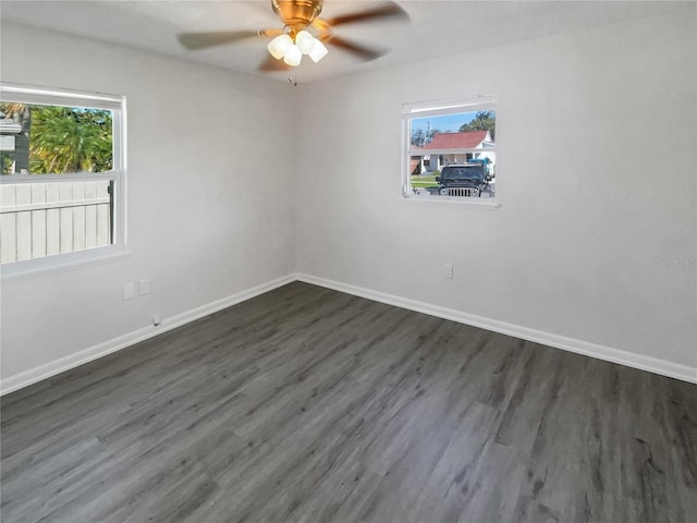 unfurnished room featuring ceiling fan, baseboards, dark wood-type flooring, and a wealth of natural light