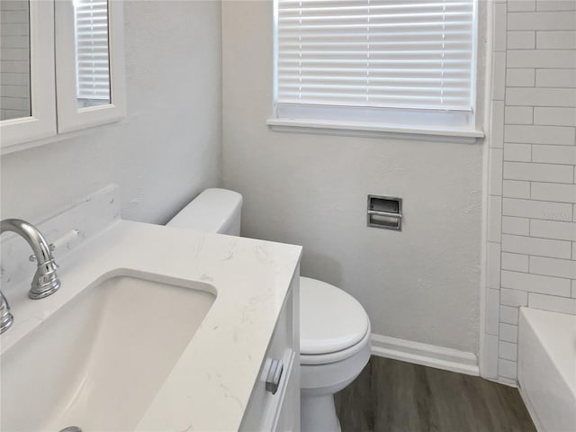 full bathroom featuring a bath, vanity, wood finished floors, and toilet