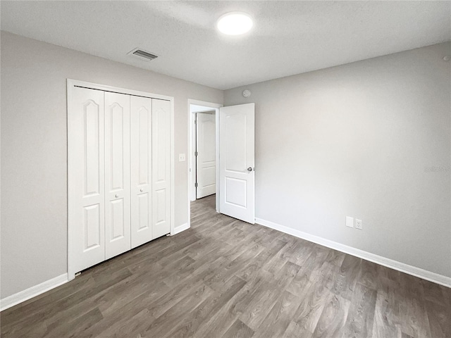 unfurnished bedroom with wood-type flooring, a textured ceiling, and a closet