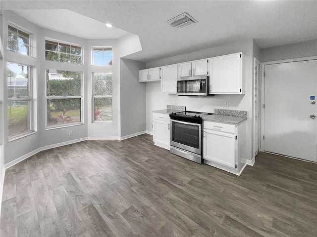 kitchen with dark hardwood / wood-style flooring, white cabinets, a textured ceiling, and appliances with stainless steel finishes