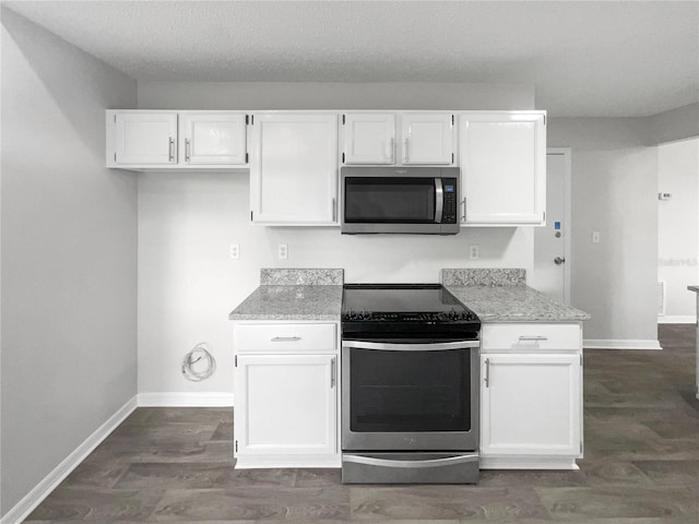 kitchen featuring white cabinets, stainless steel appliances, light stone counters, and dark wood-type flooring