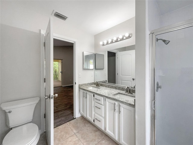 bathroom with toilet, tile patterned flooring, vanity, and walk in shower