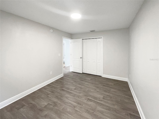 unfurnished bedroom featuring dark hardwood / wood-style flooring and a closet