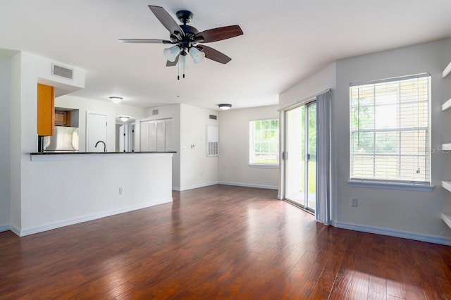 unfurnished living room featuring ceiling fan, sink, and dark hardwood / wood-style flooring