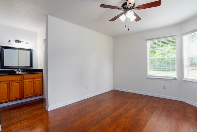 empty room featuring dark hardwood / wood-style floors, sink, and ceiling fan