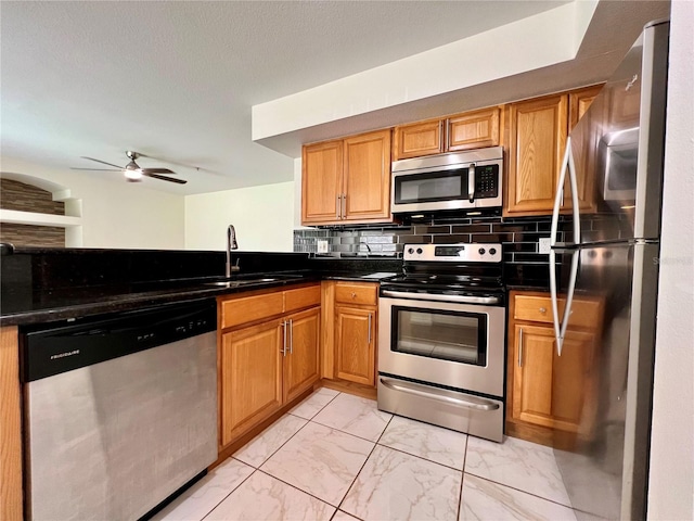 kitchen with appliances with stainless steel finishes, sink, ceiling fan, and decorative backsplash