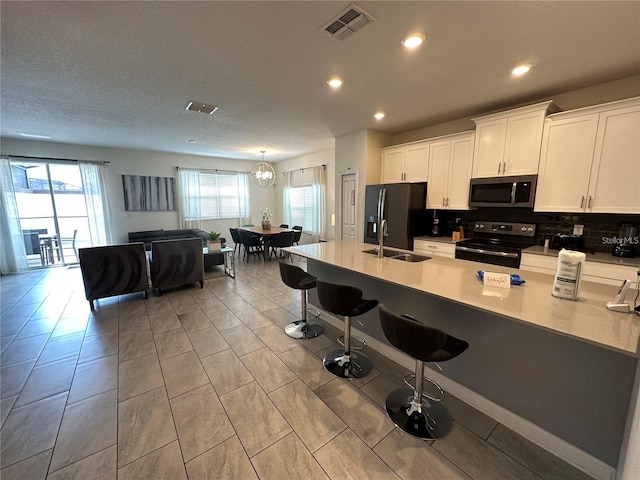 kitchen with light countertops, visible vents, appliances with stainless steel finishes, white cabinetry, and a sink