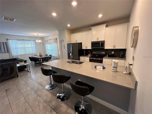 kitchen with range with electric stovetop, black fridge with ice dispenser, visible vents, light countertops, and stainless steel microwave