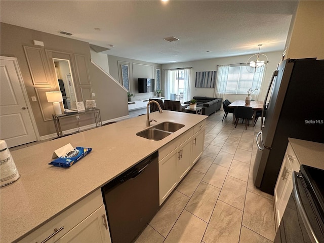 kitchen with light countertops, freestanding refrigerator, white cabinets, a sink, and dishwasher