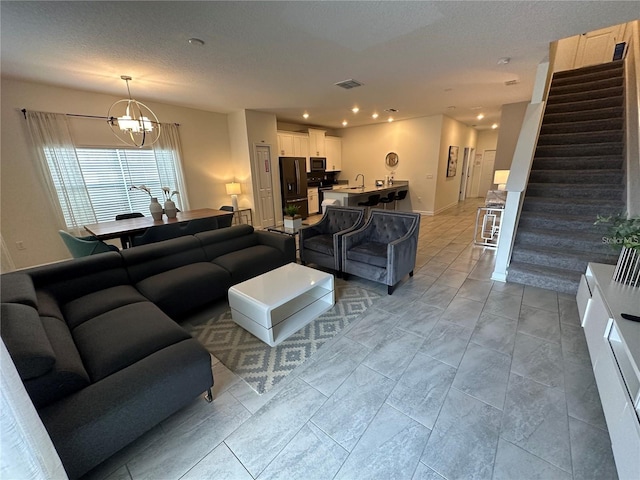 living room featuring recessed lighting, visible vents, a textured ceiling, a chandelier, and stairs