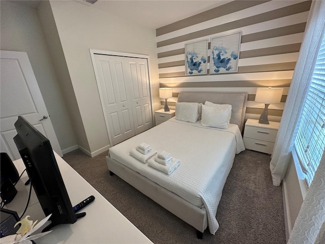 bedroom with dark colored carpet, a closet, and baseboards