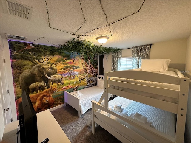 bedroom with carpet, visible vents, and a textured ceiling