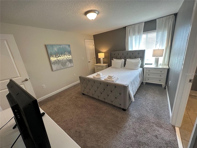 bedroom with baseboards, dark carpet, and a textured ceiling