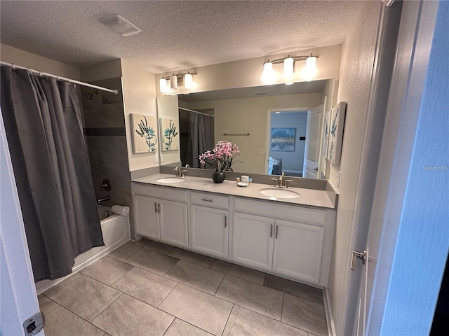 bathroom featuring a textured ceiling, double vanity, shower / bath combination with curtain, and a sink