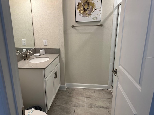 bathroom featuring a textured wall, baseboards, and vanity