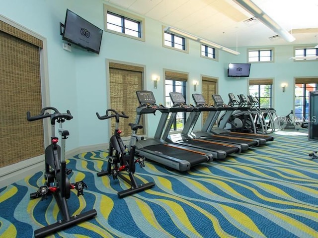 gym featuring carpet floors, visible vents, and a towering ceiling