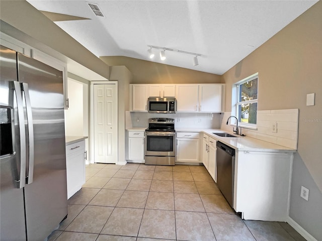 kitchen with white cabinets, decorative backsplash, lofted ceiling, and appliances with stainless steel finishes