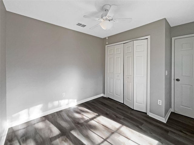 unfurnished bedroom featuring ceiling fan, a closet, and dark wood-type flooring