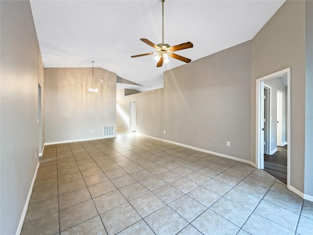 empty room with ceiling fan with notable chandelier, light tile patterned floors, and vaulted ceiling