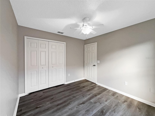 unfurnished bedroom featuring a textured ceiling, ceiling fan, a closet, and dark hardwood / wood-style floors