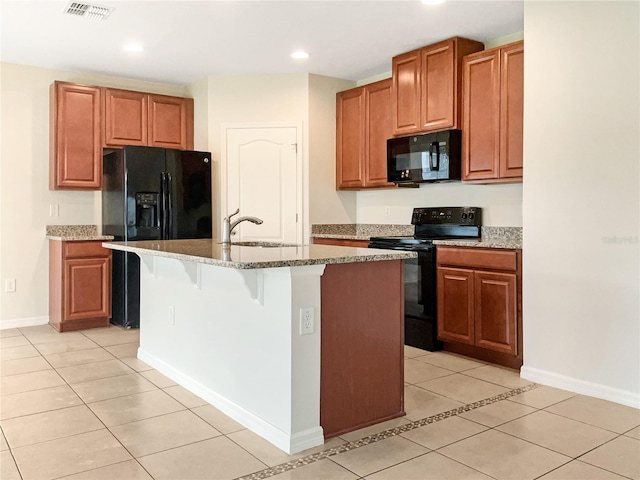 kitchen featuring sink, a breakfast bar area, a kitchen island with sink, light tile patterned floors, and black appliances