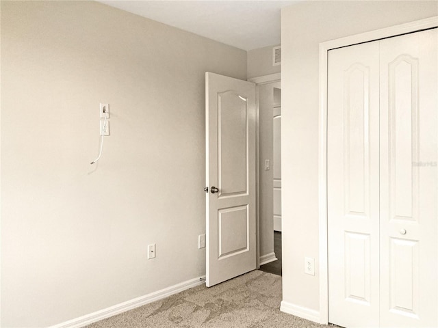 unfurnished bedroom with light carpet and a closet