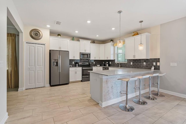 kitchen featuring a breakfast bar area, white cabinetry, hanging light fixtures, stainless steel appliances, and kitchen peninsula