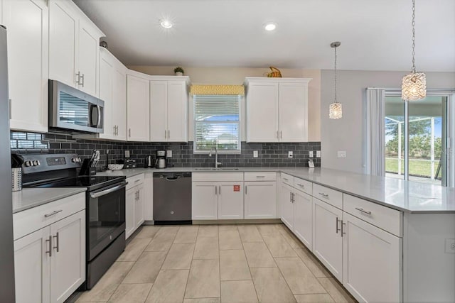 kitchen featuring white cabinetry, stainless steel appliances, decorative light fixtures, and kitchen peninsula