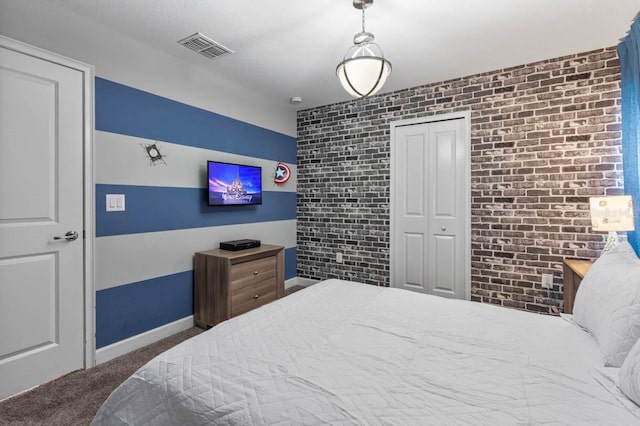 bedroom with brick wall, dark carpet, and a closet