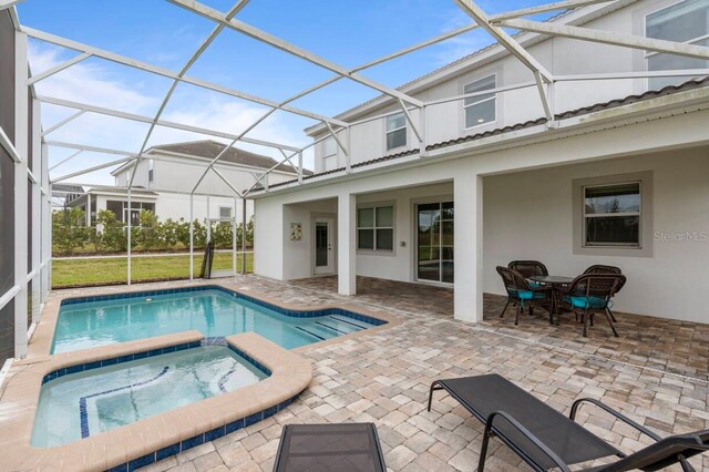 view of swimming pool with an in ground hot tub, glass enclosure, and a patio area