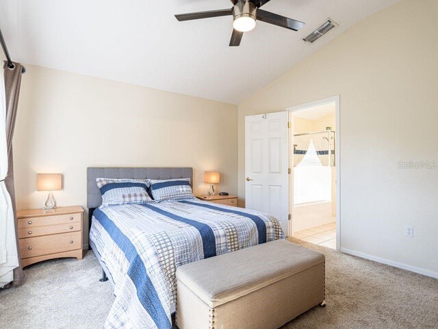 bedroom featuring ceiling fan, vaulted ceiling, light carpet, and ensuite bath