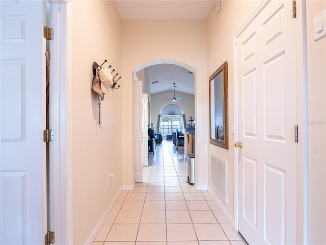 corridor featuring light tile patterned flooring and vaulted ceiling