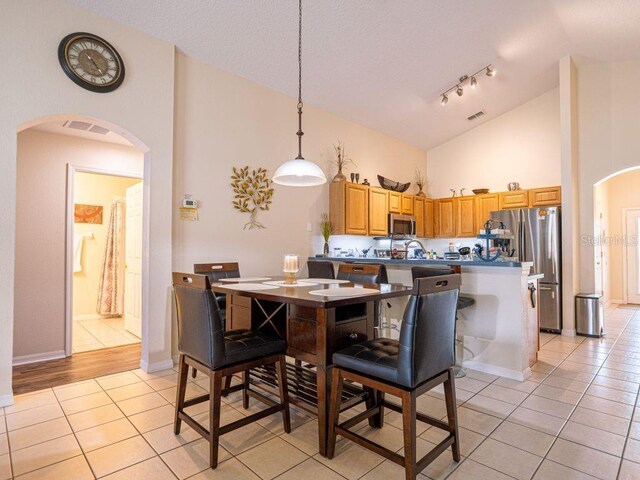 dining area featuring light tile patterned floors and high vaulted ceiling