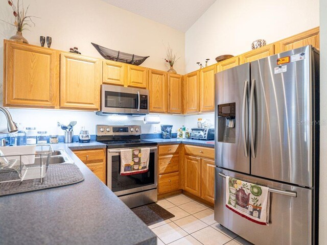 kitchen featuring light tile patterned floors, stainless steel appliances, a high ceiling, and sink