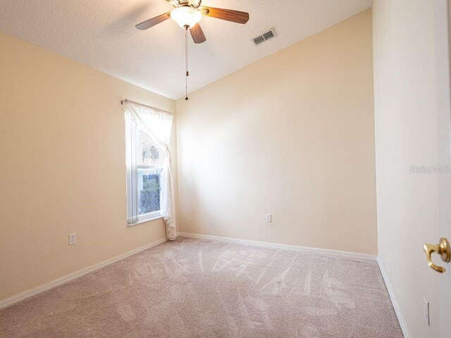 empty room with lofted ceiling, ceiling fan, light colored carpet, and a textured ceiling