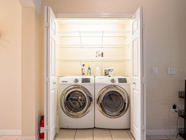 clothes washing area featuring light tile patterned floors and washing machine and dryer