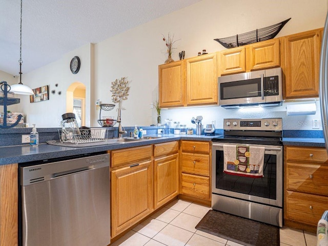 kitchen featuring light tile patterned floors, decorative light fixtures, and appliances with stainless steel finishes