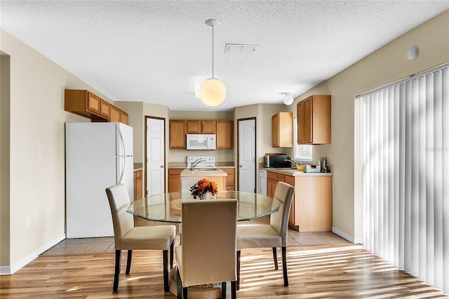 dining room with a textured ceiling and light wood-type flooring